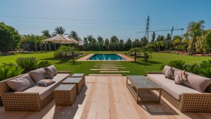 Ein Poolbereich mit Gartenmöbeln, einem Pool und einem gepflegten Rasen.