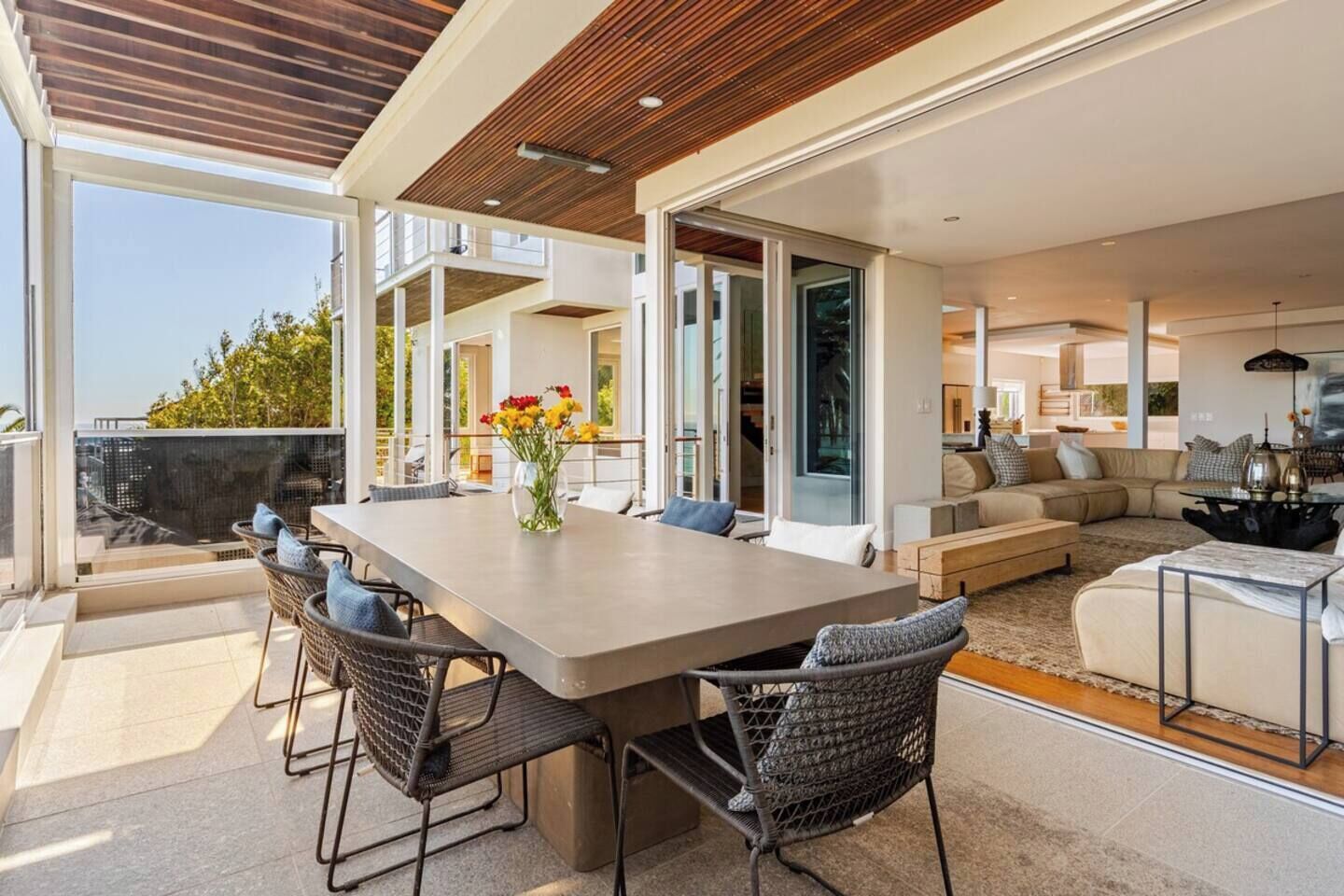A spacious living area with a large table and chairs, a sofa set, and a dining area with a view.