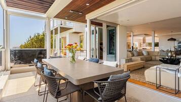 A spacious living area with a large table and chairs, a sofa set, and a dining area with a view.