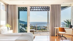 Un dormitorio con una cama grande, un escritorio y vistas al océano.
