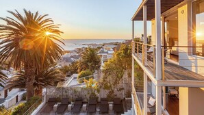 Edificio moderno con piscina y sillones de playa con vista al mar.