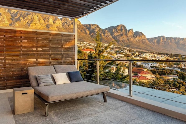 A balcony with a sofa and a view of a mountainous landscape.