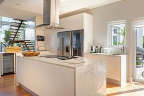 A modern kitchen with a central island, stainless steel appliances, and a view of the outdoors.