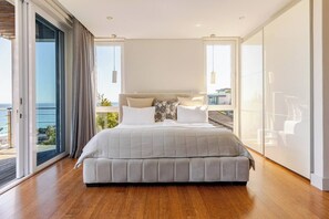 Un dormitorio con una cama grande, vista al mar y un balcón.