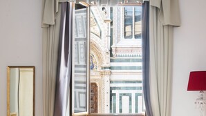 Une chambre avec une grande fenêtre, un tapis rouge et un miroir au mur.
