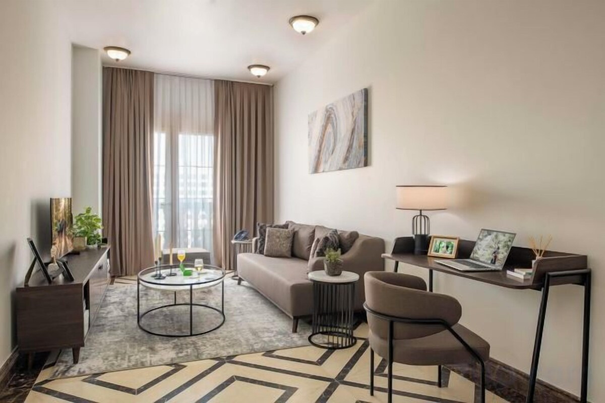 A modern living room with a sofa, coffee table, and chairs, a TV, and a lamp.