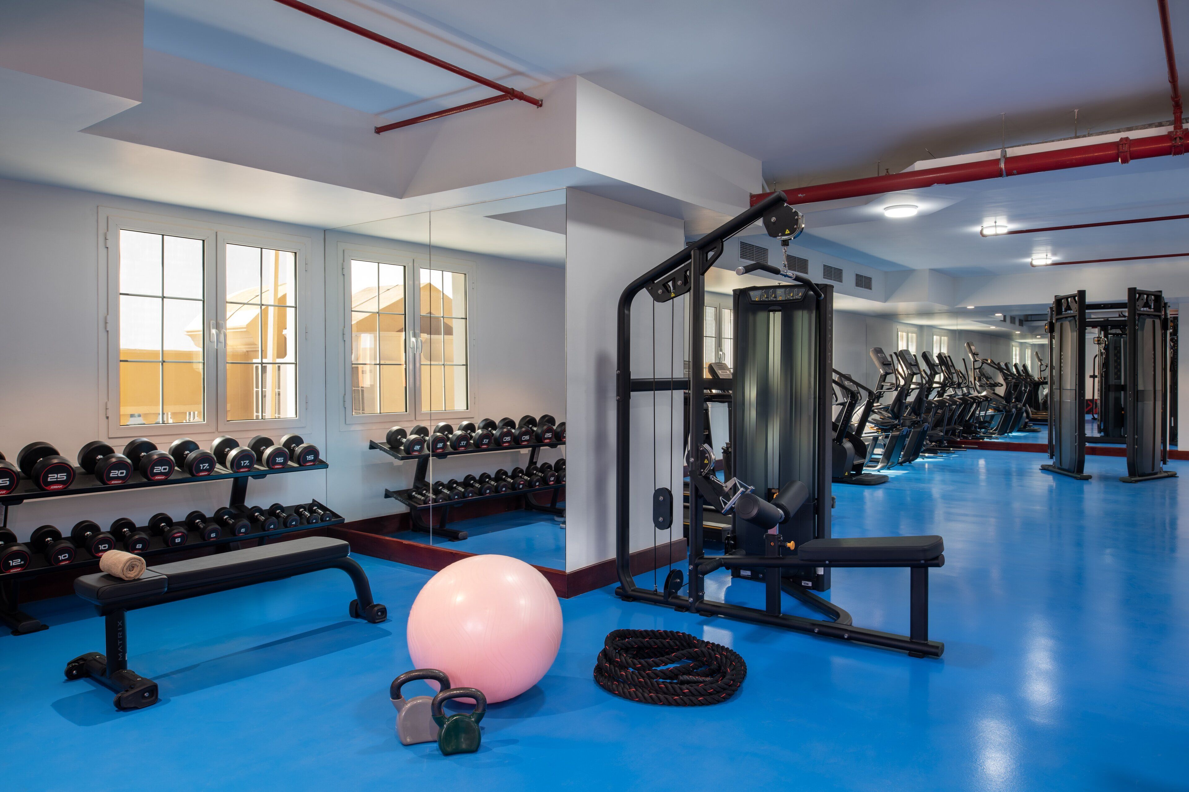 A gym with exercise equipment, dumbbells, and a large exercise ball.