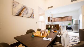 A dining area with a chessboard, a table lamp, and a painting on the wall.