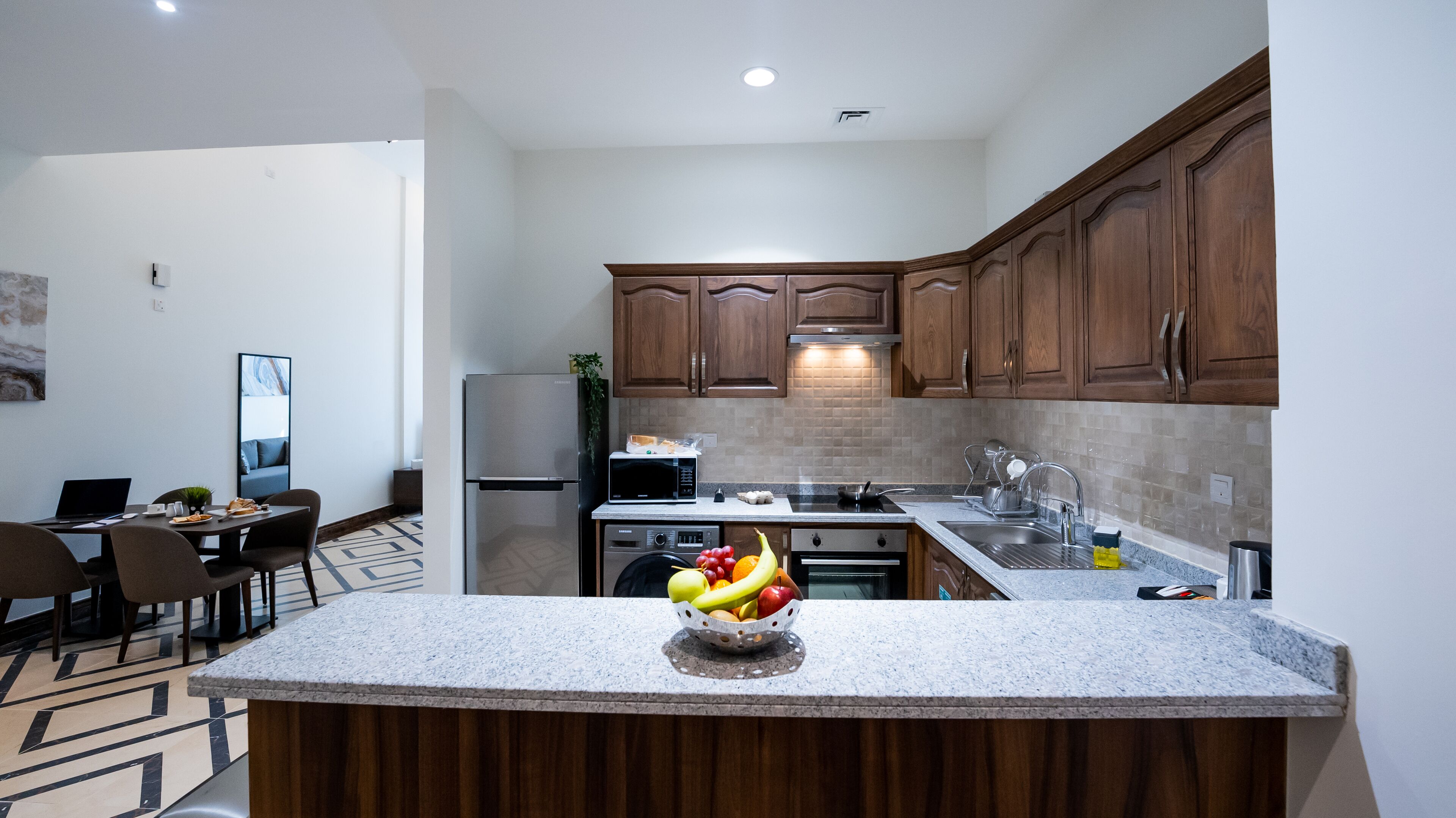 Una cocina moderna con armarios de madera, encimera de granito y un frutero.