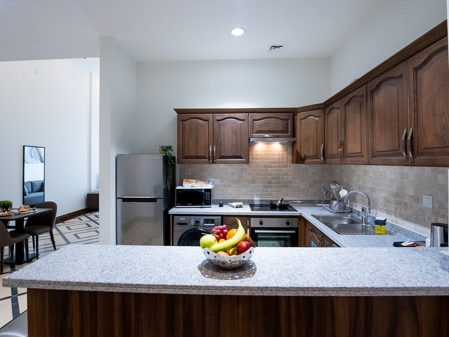 Una cocina moderna con armarios de madera, encimera de granito y un frutero.