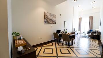 A modern hotel room with a dining area, a large mirror, and a marble artwork on the wall.