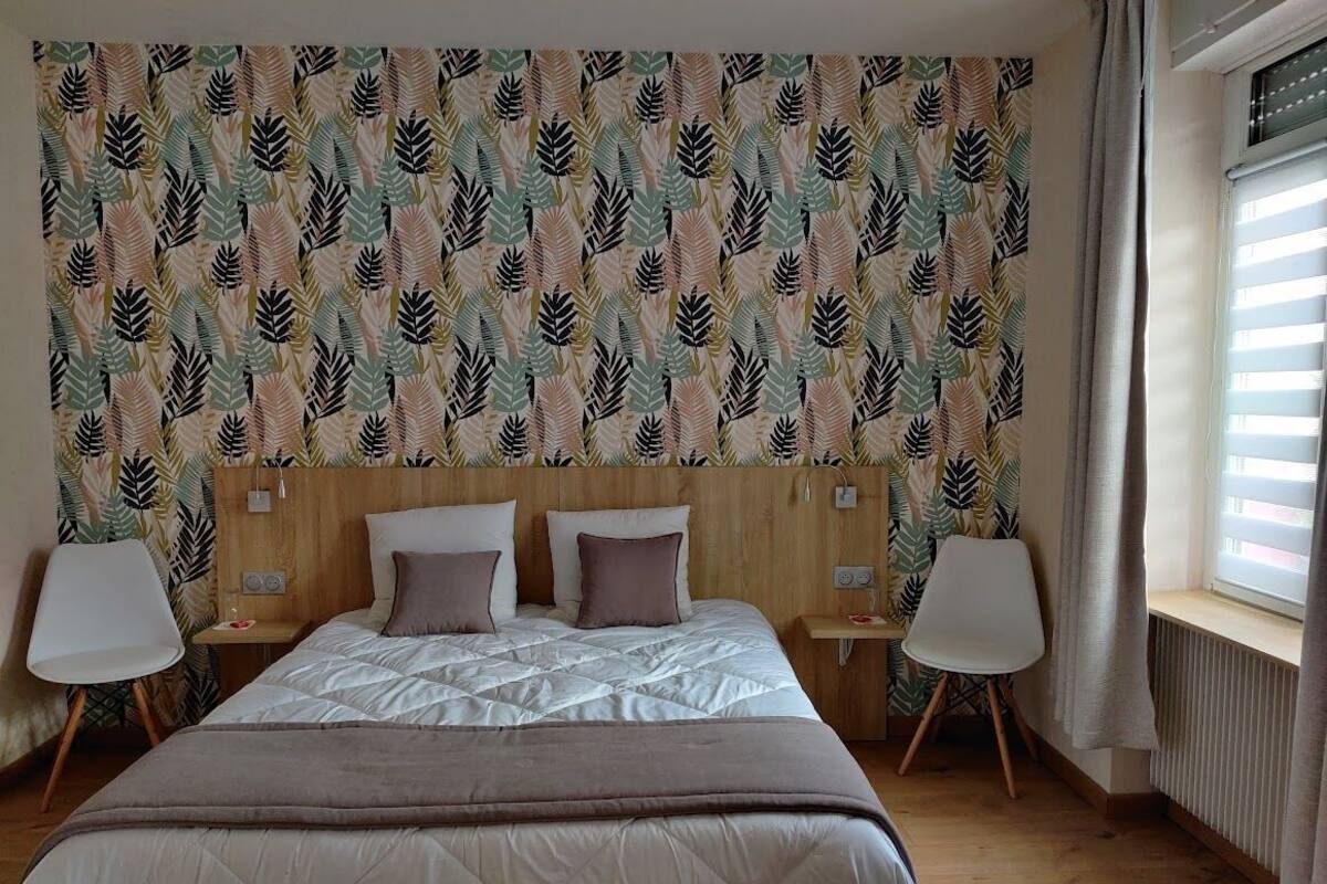 Quarto com cama, duas mesas de cabeceira e janela com persianas.