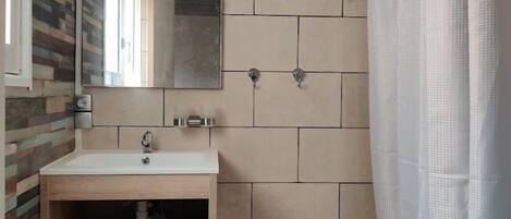 A bathroom with a wooden vanity, a mirror, and a shower curtain.