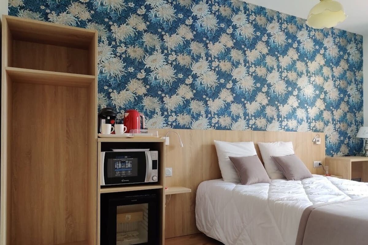 Quarto com cama, prateleiras de madeira, micro-ondas e cafeteira.
