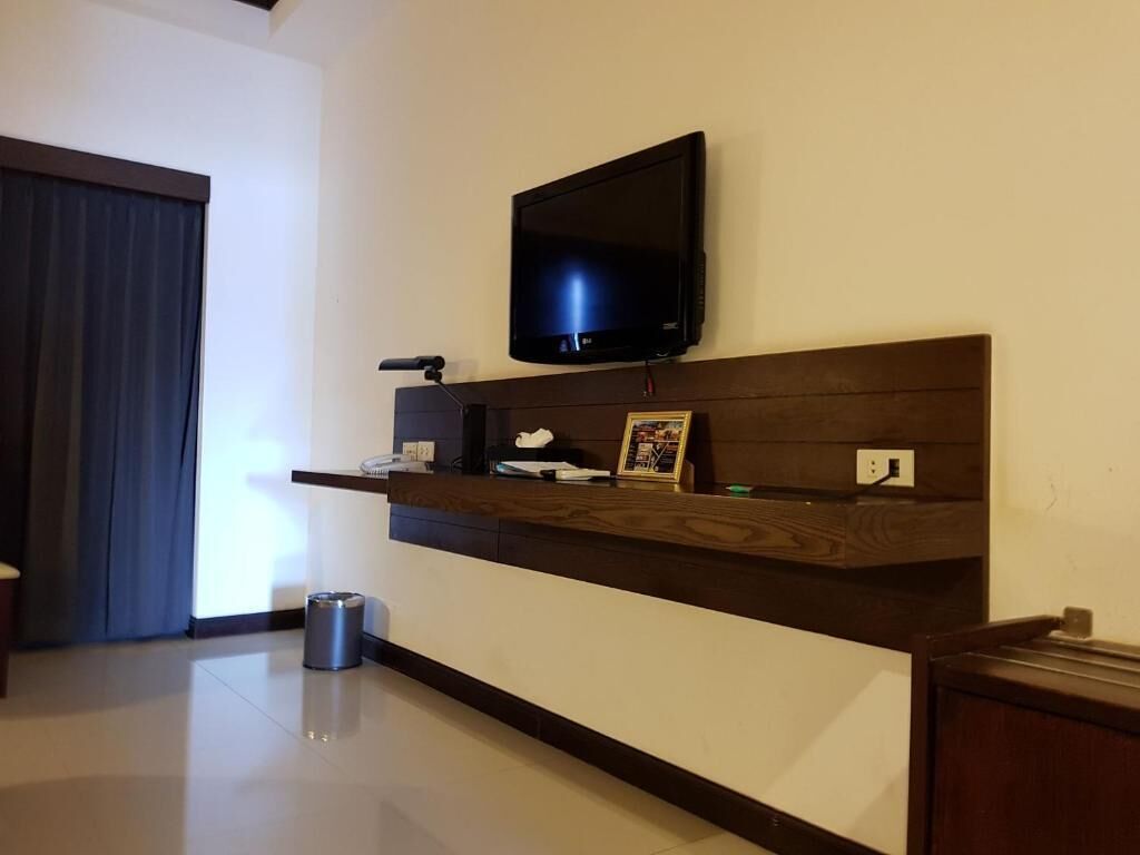 Una sala moderna con un televisor de pantalla plana montado en un estante de madera, un cubo de basura pequeño y un cuadro enmarcado en el estante.