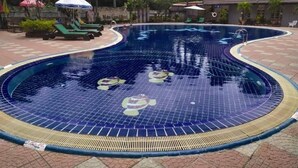A swimming pool with a tiled edge and a circular design, surrounded by lounge chairs and umbrellas. - Major Grand Hotel (Chum Phae)
