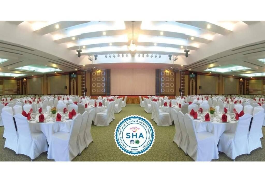 Une salle de banquet avec des tables rondes, des nappes blanches et des serviettes rouges.