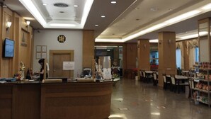 A spacious lobby with a curved reception desk, multiple seating areas, and a visible clock on the wall. - Major Grand Hotel (Chum Phae)