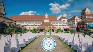 A hotel with a central courtyard, white chairs arranged in rows, and a logo indicating it is a SHA certified hotel. - Major Grand Hotel (Chum Phae)