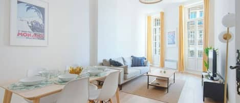Una sala de estar moderna con comedor, sofá y televisión.