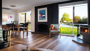 Una sala de estar moderna con chimenea, comedor y ventanas amplias que ofrecen vistas al exterior.