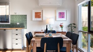 Un comedor con una mesa de madera, sillas, una botella de vino, copas y obras de arte en las paredes.