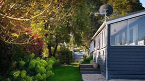 Una casa moderna con antena parabólica, rodeada de abundante vegetación y un césped cuidado.