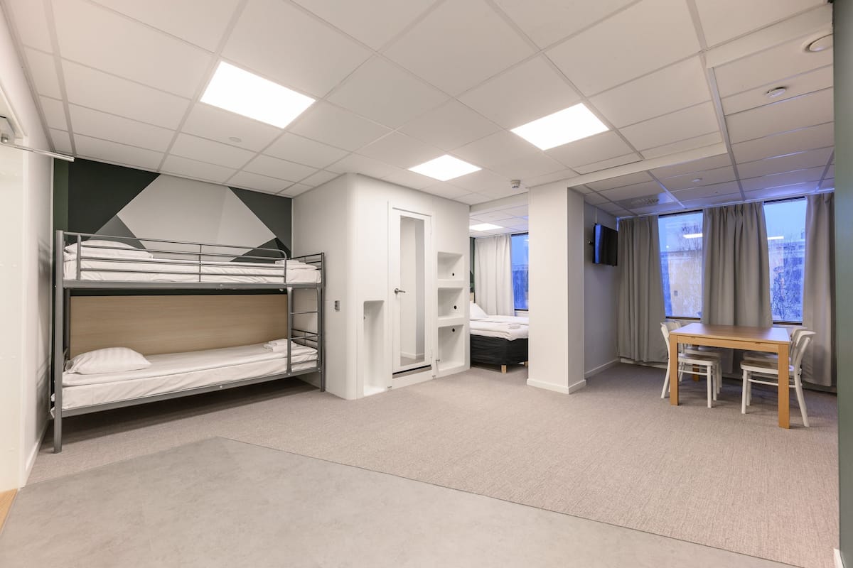 Een hotelkamer met stapelbedden, een bureau en een stoel.