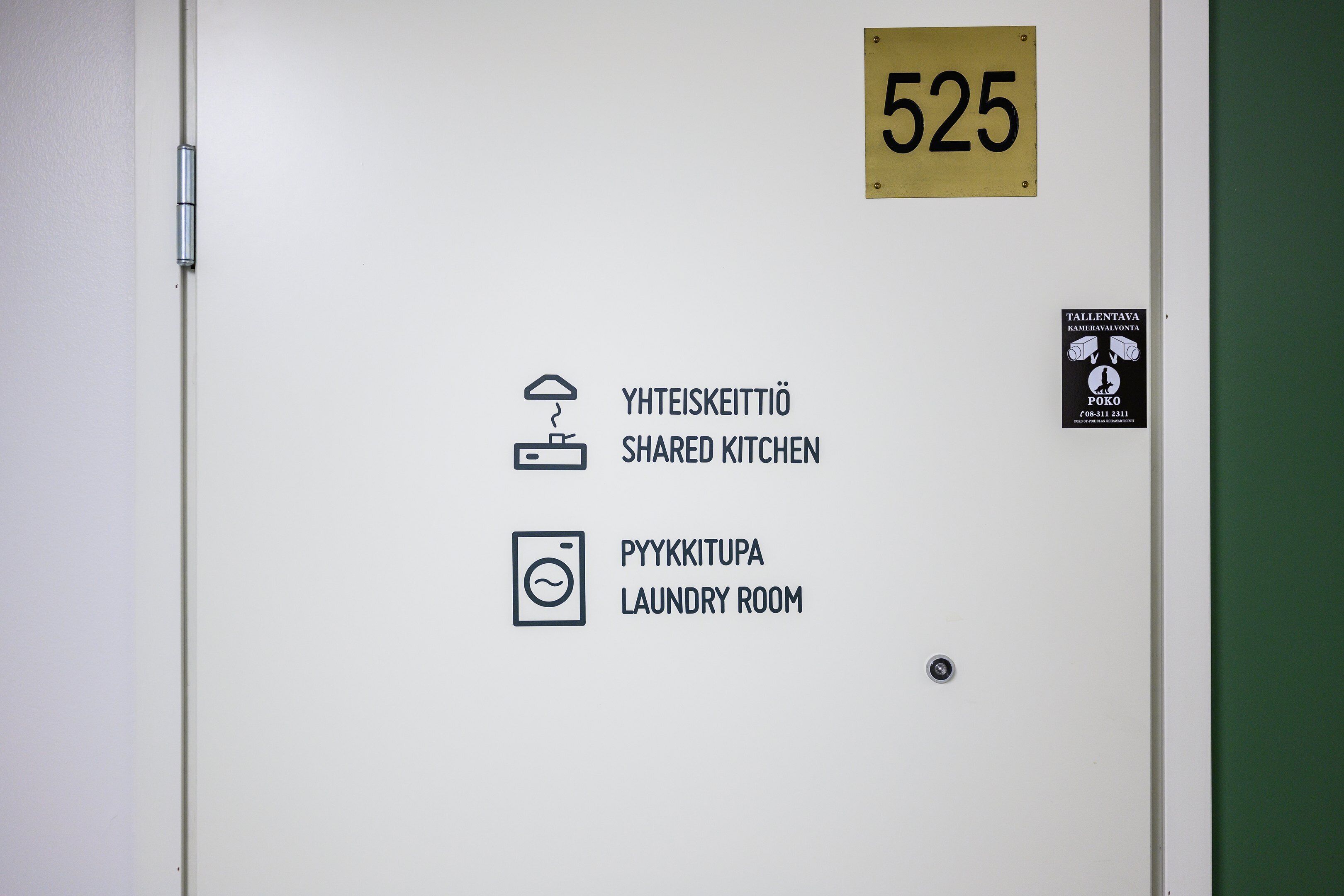 A door with a number plate labeled '525', a sign for a shared kitchen, and a laundry room.