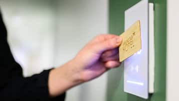 En hand håller i ett kort med texten ”GreenStar Hotel” på, och kortet ligger på en kortläsare.