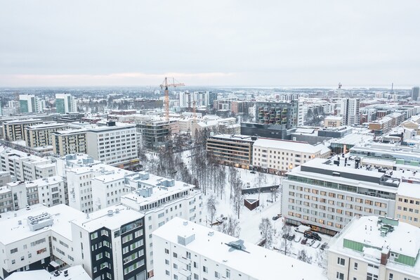 Un paisaje urbano con rascacielos, una grúa de construcción y tejados cubiertos de nieve.