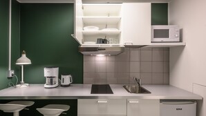 A modern kitchen with white cabinets, a built-in microwave, a coffee maker, and a sink.