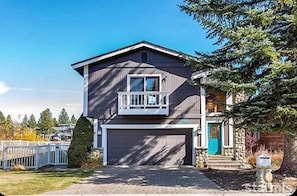 A two-story house with a garage, a balcony, and a stone foundation. - Waterfront Home on Double Lot - Boat Dock, Hot Tub and More! (South Lake Tahoe)