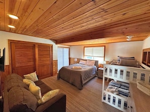 A cozy bedroom with a wooden ceiling, a large bed, a sofa, and a white storage unit. - Waterfront Home on Double Lot - Boat Dock, Hot Tub and More! (South Lake Tahoe)