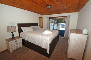 Ein Schlafzimmer mit Holzboden, einem Bett mit gemustertem Bettbezug, einem Nachttisch mit Schubladen und einem Holzschrank.