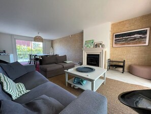 Un salon comprenant un canapé, une table basse, une cheminée et un coin repas avec des chaises.