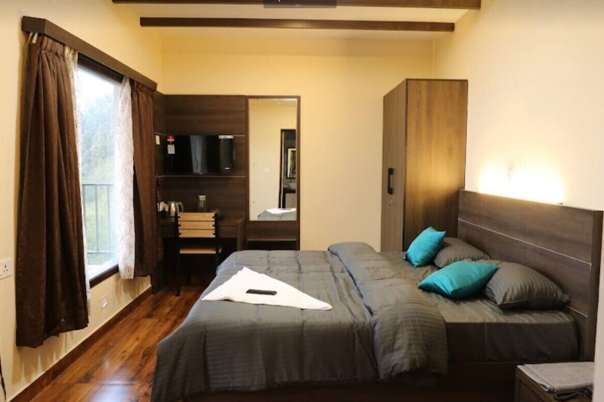 A bedroom with a bed, a wardrobe, a mirror, and a window with curtains.