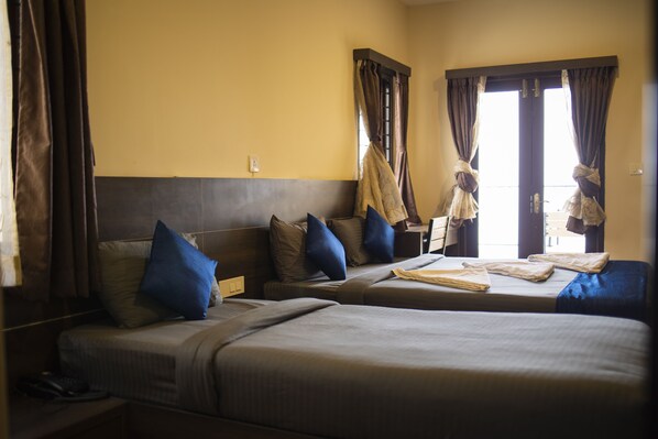 Una habitación de hotel con dos camas, una mesita de noche, un teléfono y cortinas.