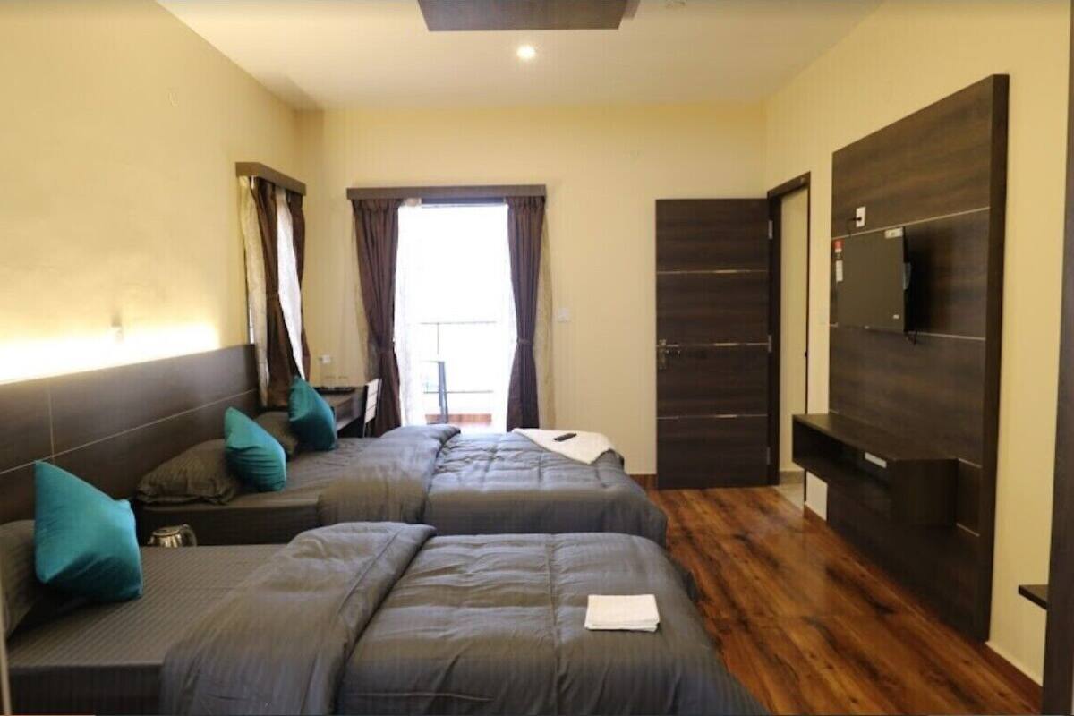 A hotel room with two beds, a TV, a wardrobe, and a window with curtains.