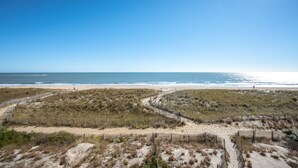 A beach with a wooden fence, sandy dunes, and the ocean.