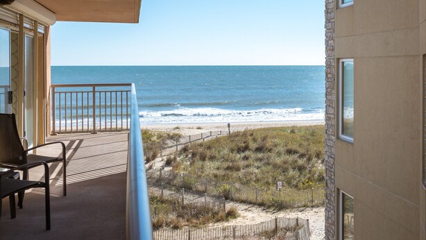 A balcony with a view of the beach and ocean.
