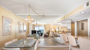 A spacious living area with a dining table, multiple chairs, a sofa, and a television.