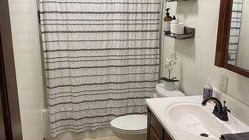 Een bad/douchecombinatie, een haardroger, handdoeken, zeep