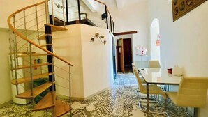 Un intérieur moderne avec un escalier en colimaçon, un coin repas et un revêtement de sol à motifs.