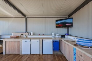 A modern kitchen with built-in appliances, a flat-screen TV mounted on the wall, and a wooden floor. - Family home with hydromassage pool &fun activities (Domijanići)