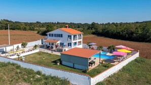 A two-story house with a swimming pool and outdoor umbrellas. - Family home with hydromassage pool &fun activities (Domijanići)