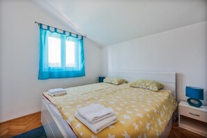 A single bed with a yellow star-patterned bedspread, two pillows, a blue curtain, a bedside table with a lamp, and a window with a blue curtain. - Family home with hydromassage pool &fun activities (Domijanići)