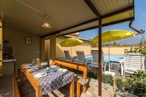 Un espace extérieur aménagé pour les repas, avec une piscine et des chaises longues.