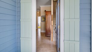 A hallway with light blue siding, a wooden door, and a beige tiled floor. - 1016 San Fernando Street 3 Bedroom Home by RedAwning (Fernandina Beach)