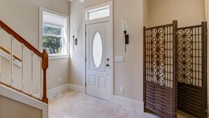 A hallway with a white door, a window, and a decorative wooden gate. - 1016 San Fernando Street 3 Bedroom Home by RedAwning (Fernandina Beach)
